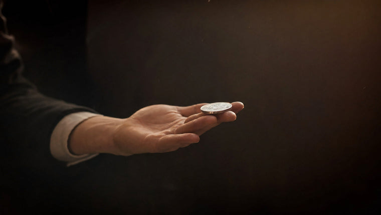 A silver coin balanced on the fingertips of an open hand