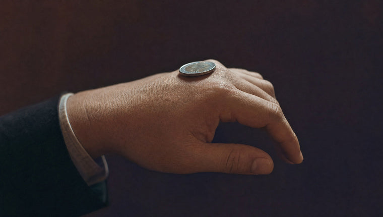 A silver coin resting across the knuckles on the back of a hand