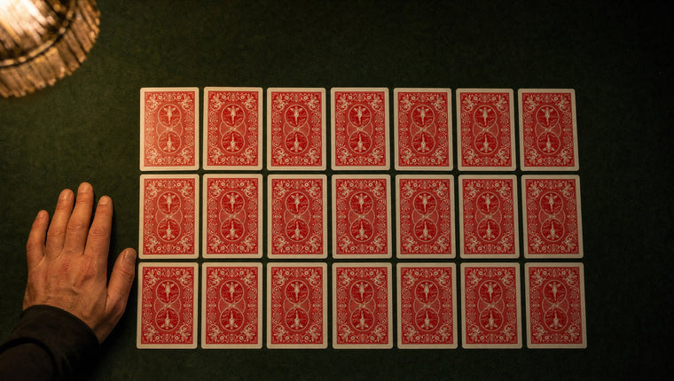 Twenty-one red-backed playing cards laid face down in three rows of seven on green baize