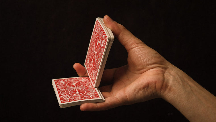 One hand in mid-air doing a one-handed cut, half the deck on the palm and half raised on the thumb