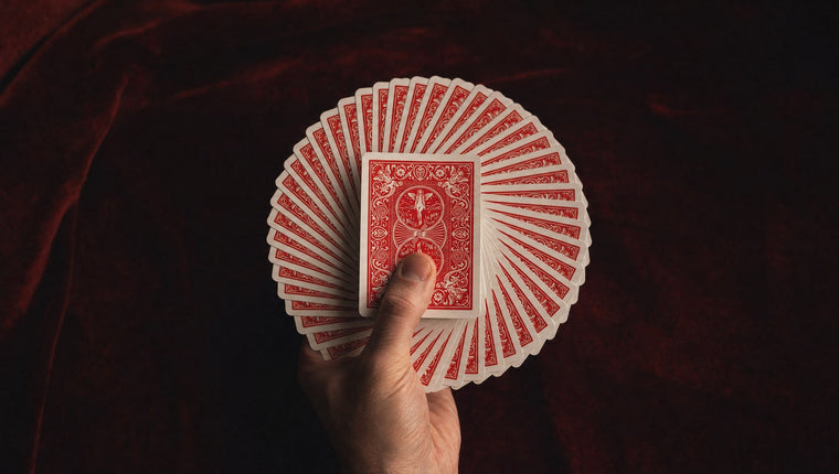 A full circular fan of red-backed playing cards held in one hand