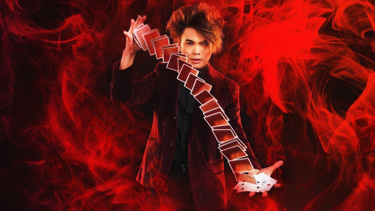 Shin Lim springing a long cascade of cards from one hand to the other against red smoke