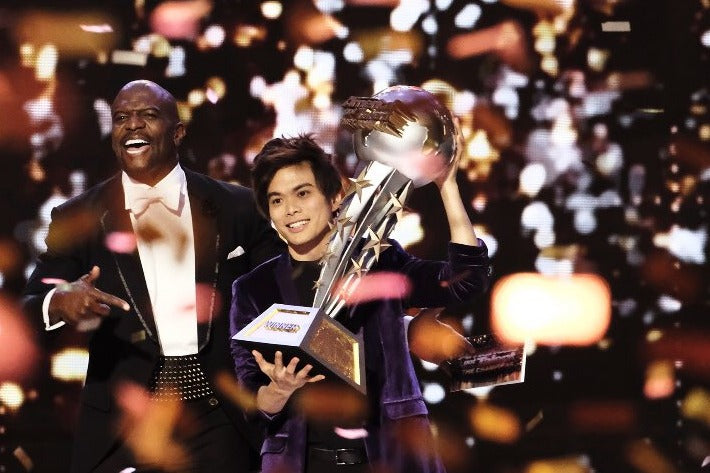 Shin Lim holding the America's Got Talent: The Champions trophy