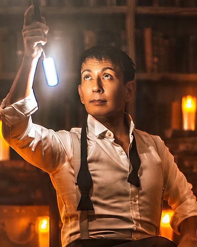 Cyril Takayama holding up a light, surrounded by candles